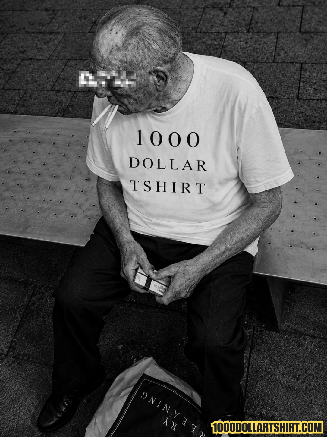 Black and white documentary-style photograph of an elderly man wearing a 1000 Dollar T Shirt while sitting alone on a public bench with three unlit cigarettes in his mouth and a cigarette pack in his hands.