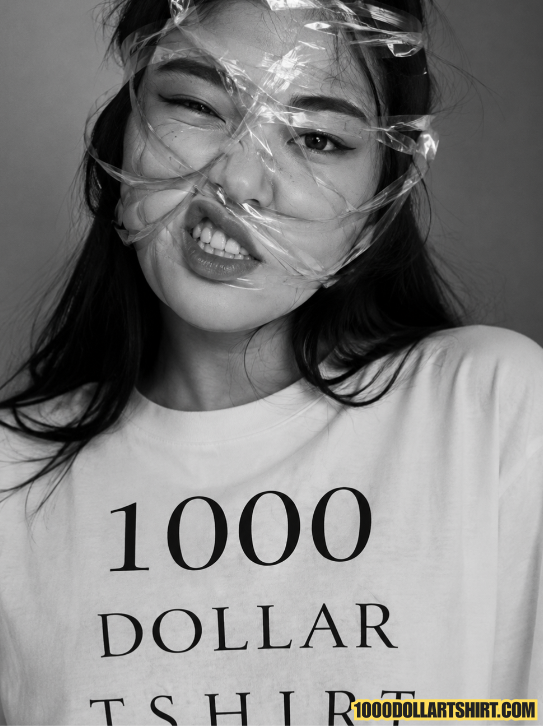 Close-up black and white photograph of a woman with plastic wrap around her face, wearing a white t-shirt printed with '1000 DOLLAR TSHIRT' in bold black letters and a 1000DOLLARTSHIRT.COM logo in the corner.